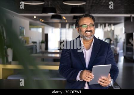 Cheerful elder Indian businessman using tablet computer Stock Photo