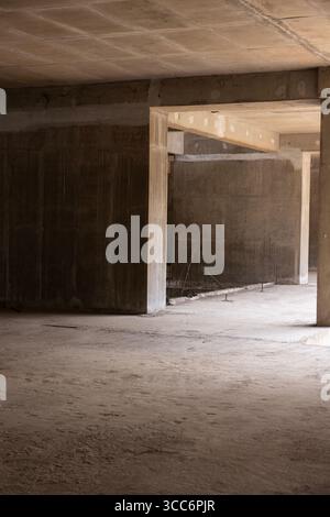 Unfinished concrete interior of a building under construction. This raw space with walls and beams highlights the early stages of a new project. Stock Photo