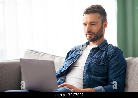 Concentrated man using computer, having part time job at home Stock Photo