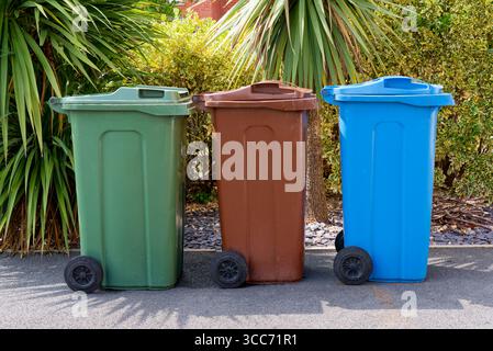 Three waste recycling wheelie bins. Green, (garden), brown, (paper and cardboard) and blue, (tins, plastic and glass) in Lancashire, UK Stock Photo