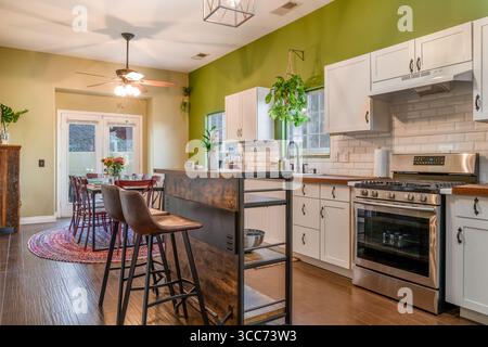 Home kitchen open floor plan dining table, breakfast bar stools, cabinets, and stove Stock Photo
