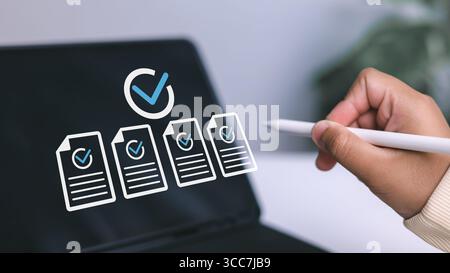 Quality control, task completion, and successful audit in modern workflow. Hand holding stylus pen pointing to digital screen with documents and check Stock Photo