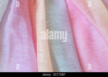 Colorful piece of tulle fabric with a rainbow pattern. The colors are pale pink, yellow, and green Stock Photo