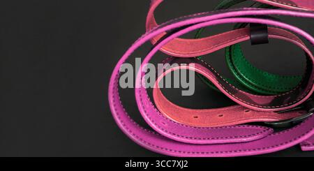 Leather belts on a black background. Abstract, artistic mosaic of belts. Twisted handmade belts made of patterned leather. Blurred image Stock Photo