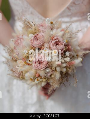 Close-up of a bridal bouquet with soft pink roses, dried flowers, and delicate textures. Perfect for wedding invitations, floral design, romantic Stock Photo