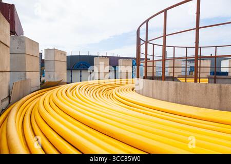 New powerful high-voltage cable in yellow braiding twisted on the ground. Stock Photo