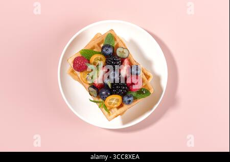 Sweet Belgian waffles with fresh berries on pink background. Top view. Desserts.  Stock Photo