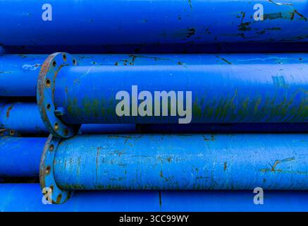 Close-up view of weathered blue water pipes stacked with rust and moss details. Stock Photo