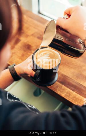 Barista Finishing Latte Art in Black Ceramic Cup Stock Photo