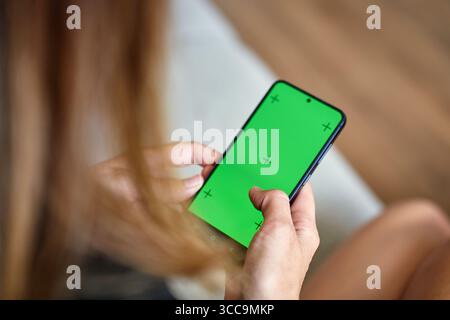 Close-up of woman using smartphone with green screen. Female hands holding mobile phone indoors Stock Photo