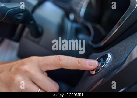 Close-up of hand pressing start button to turn on car engine. Keyless ignition system in modern car Stock Photo