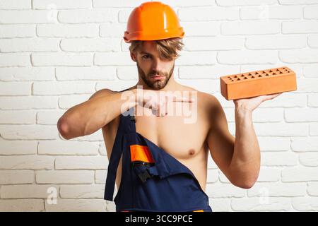 Crazy builder with bricks, funny sale on construction site. Funny man hold brick. Builder posing with bricks blocks. Bricklayer concept. Funky Stock Photo