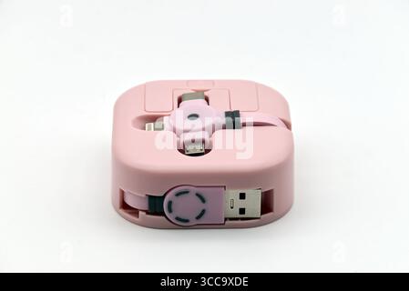 A pink portable multi-charging cable with various connectors designed for mobile devices is presented on a clean white background. Stock Photo
