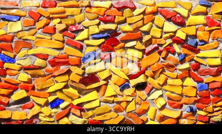 Handmade mosaic tiles detail. Small colorful glass and stone pieces crafted into pattern of yellow, blue and red color Stock Photo