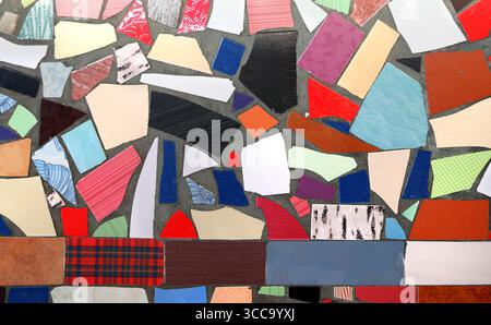 Colorful tile pieces crafted into pattern. Handmade mosaic tiles detail. Tile-shard panno. Pieces of broken tiles on wall forming a colorful mosaics Stock Photo
