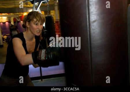 A young woman practices boxing with a  punching bag Stock Photo