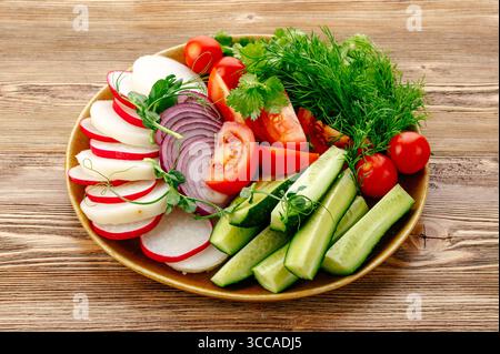 Assorted fresh vegetables on a plate with greens Stock Photo