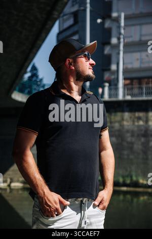 Bearded man wearing cap and sunglasses in city Stock Photo