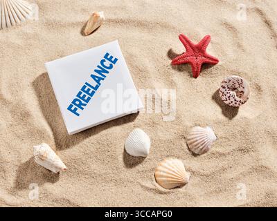 Freedom, flexibility and freelance work. White sign with inscription freelance lying on beach sand surrounded by sea shells and starfish Stock Photo