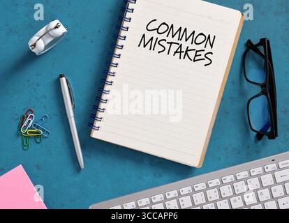Notepad displaying common mistakes surrounded by stationery and computer keyboard on a vibrant blue desk, promoting error-free work Stock Photo
