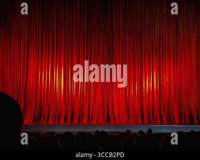 Red theater curtains on stage with spotlight shining before stage performance begins. Background. Concept of anticipation, performing arts, cultural e Stock Photo