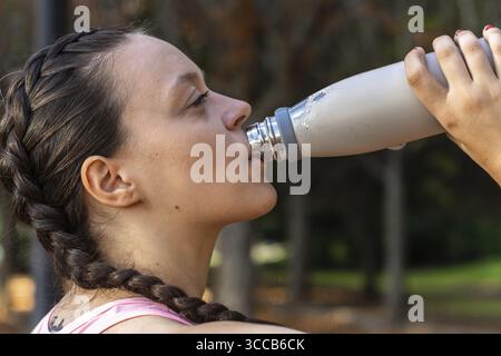 Fitness woman drinks water from a bottle after training Stock Photo