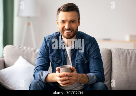 Relaxed handsome man drinking coffee in living room Stock Photo