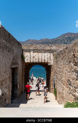 Spinalonga, Crete, Greece - June 26, 2025: Visitors walk through ancient stone walls to admire the sea view on Spinalonga island. Stock Photo