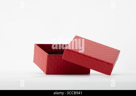 An open red gift box with its lid slightly askew, set against a clean white background Stock Photo