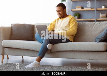 Black guy spending time at home, using laptop Stock Photo