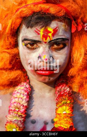 Chandanath hill, Bangladesh - 12 March 2021: View of a person adorned with vibrant orange hair and a garland, their face painted in stark white with s Stock Photo