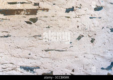 Old beige plaster wall texture with stone fragments and natural cracks. Stock Photo