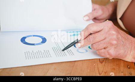 Senior Woman Analyzing Financial Report with Graphs and Charts Stock Photo