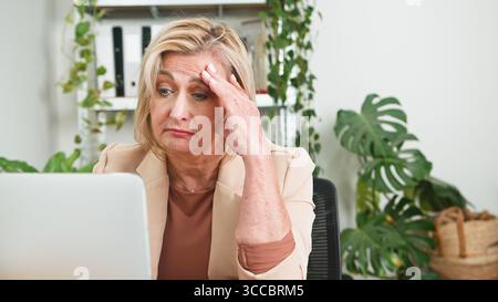 Senior Businesswoman Looking Concerned While Working on a Laptop Stock Photo
