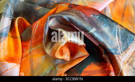 Textile silk scarf. Yellow, orange, brown handmade texture fabric. Cloth background. Stock Photo