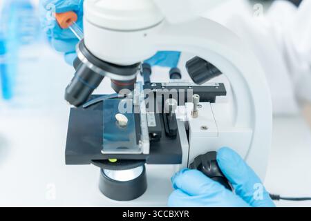 Scientist analyze biochemical samples in advanced scientific laboratory. Medical professional use microscope look microbiological developmental of vir Stock Photo