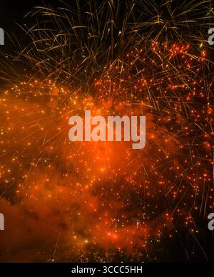 Colorful fireworks explosion lighting up the night sky with golden and red sparks Stock Photo