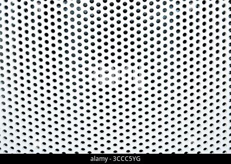 Close-up of a perforated metal surface with a geometric pattern of circular holes Stock Photo