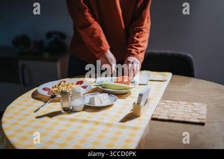 Young person preparing a meal at a table with breakfast dishes Stock Photo