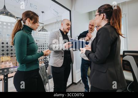 Group of colleagues discussing over documents during a team meeting in a modern office environment Stock Photo