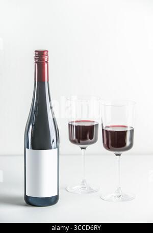 Red wine setting with bottle and two wine glasses on table at white background. Front view with copy space. Stock Photo