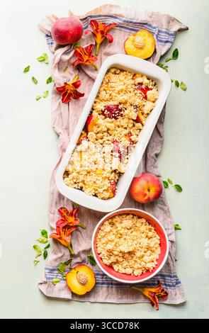 Fresh whole and halves of peaches with baking pan and shortbread dough on light background, top view. Fruits cake or pie baking concept Stock Photo