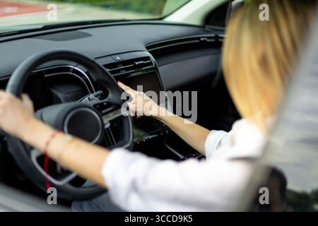 Businesswoman driving a modern car and using the touchscreen navigation system while holding the steering wheel Stock Photo