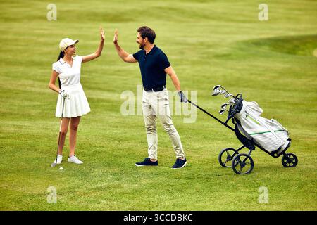 An enthusiastic group of golfers joyfully share a highfive on a lush, green golf course, perfectly embodying the spirit of camaraderie and happiness t Stock Photo