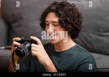 Smiling man with curly hair checking camera indoors Stock Photo