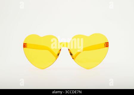 Stylish yellow heart-shaped sunglasses are displayed on a clean white background, adding a touch of fun and whimsy Stock Photo