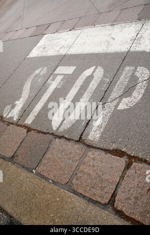 Faded stop sign painted on asphalt in front of a pedestrian crossing, indicating traffic regulations and pedestrian safety Stock Photo