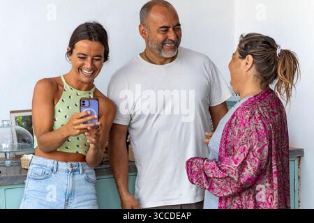 Cheerful family members sharing a funny moment while using a smartphone Stock Photo