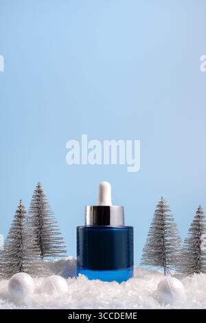 Winter skincare beauty concept with face serum on a blue background, front view, copy space Stock Photo