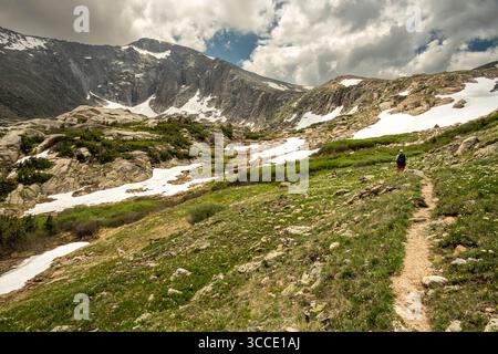Hiker Heading To The Snow Covered Crystal Lake in Rocky Mountain National Park Stock Photo